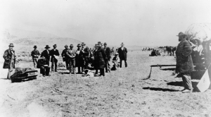 Photograph of Lee's execution at the massacre site. Lee is at the left, sitting on his coffin.